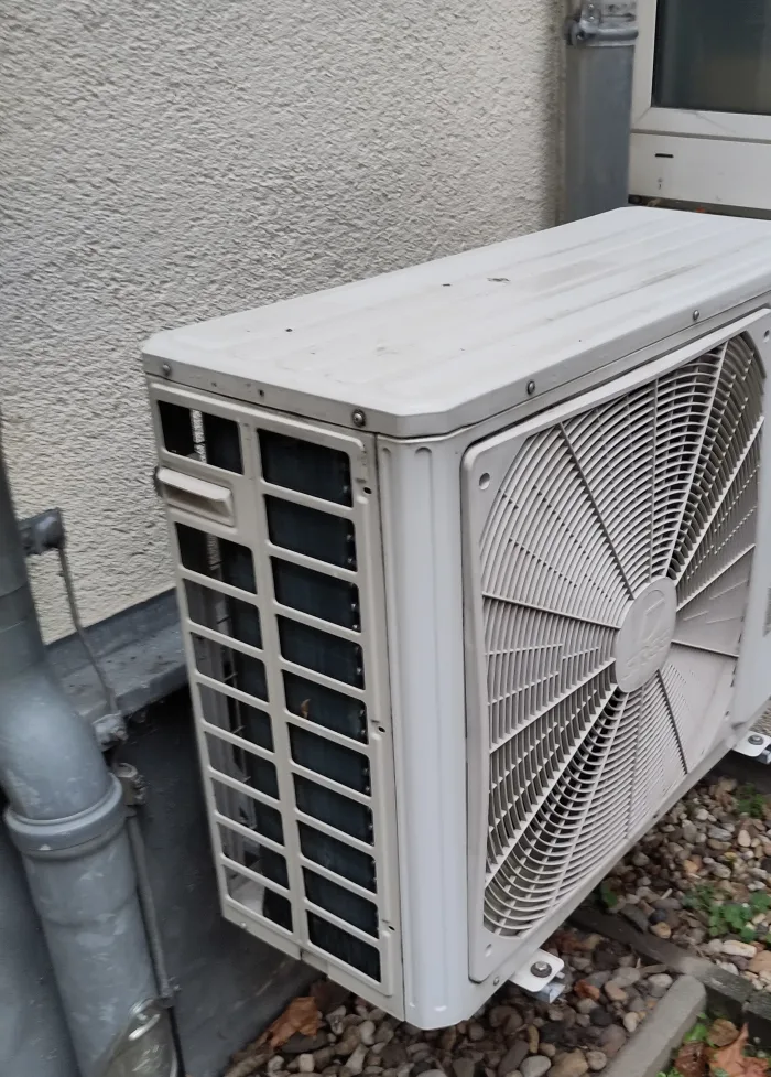 Split-system outdoor air-conditioning unit mounted beside an exterior wall